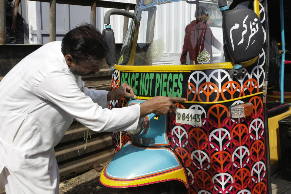 In this Saturday, Feb. 2, 2013 photo, Pakistani artist Nusrat Iqbal puts final touches to a rickshaw in Karachi, Pakistan. Pakistani youth leader Syed Ali Abbas Zaidi has an innovative plan to counter the relentless message of violence spewed forth by radical Islamic groups in the country and is stealing a trick from their playbook to do it. His weapon: the three-wheeled motorized rickshaws that buzz along Pakistan’s streets carrying paying customers. (AP Photo/Fareed Khan)