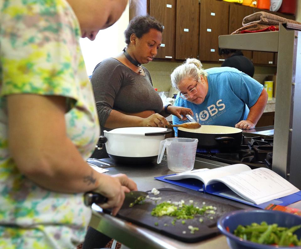 Jennifer Herrick, executive director of Jump on Board for Success, right, helps Jasmine Kirk cook a dish during class.