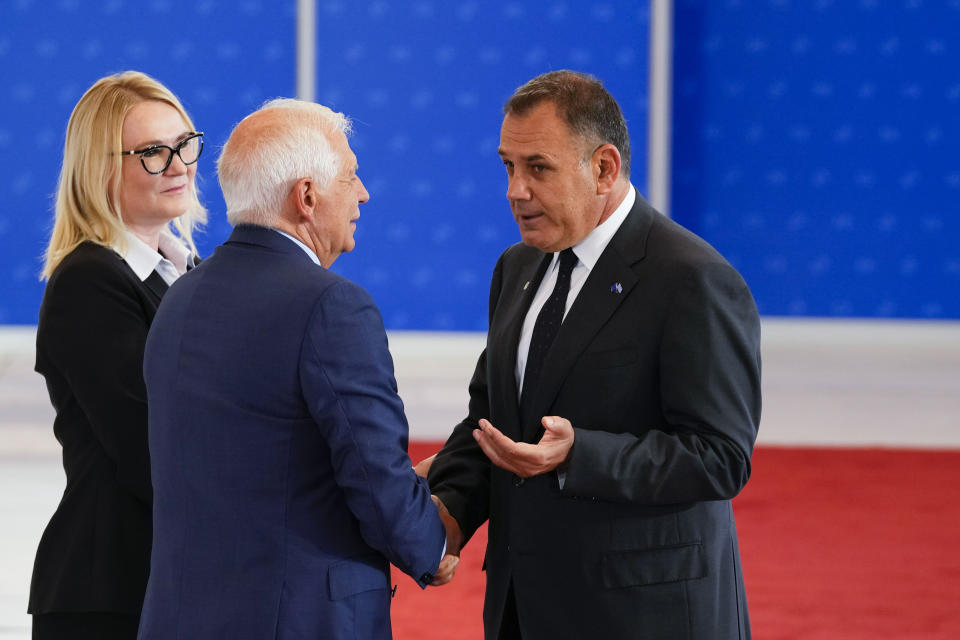 Greek Defense Minister Nikolaos Panagiotopoulos, right, shakes hands with European Union foreign policy chief Josep Borrell as he arrives for a meeting of EU Defense Ministers at the Prague Congress Center in Prague, Czech Republic, Tuesday, Aug. 30, 2022. (AP Photo/Petr David Josek)