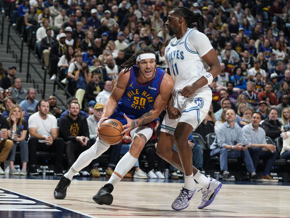 Denver Nuggets forward Aaron Gordon, left, drives to the basket as Minnesota Timberwolves center Naz Reid defends in the first half of an NBA basketball game Friday, March 29, 2024, in Denver. (AP Photo/David Zalubowski)