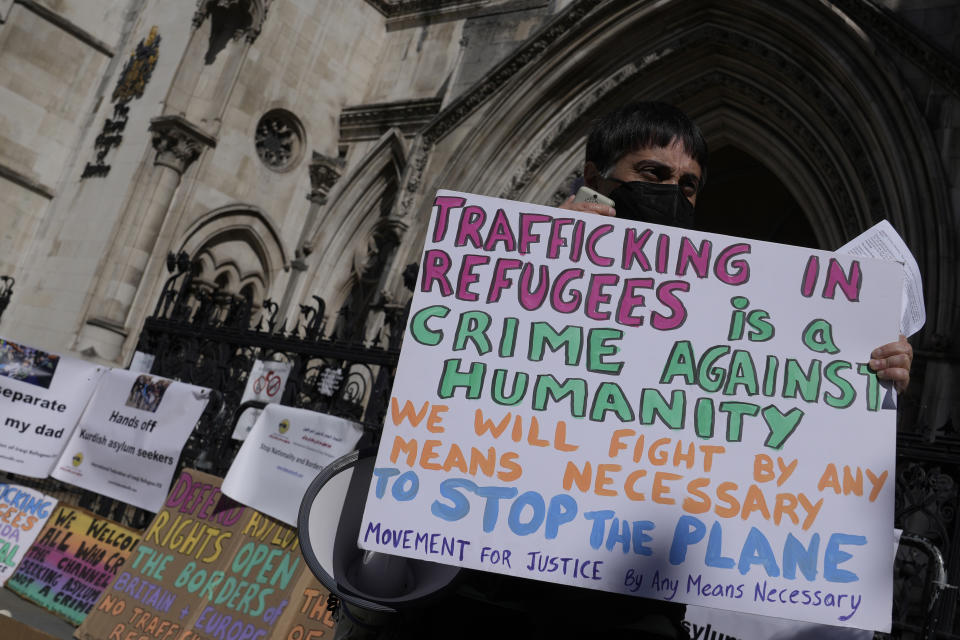 A protester stands outside the High Court where the ruling on Rwanda deportation flights is taking place, in London Monday, June 13, 2022. Opponents of the British government’s plan to deport migrants to Rwanda prepared for an appeals court hearing Monday amid the political backlash following reports that Prince Charles had privately described the policy as “appalling.” (AP Photo/Alastair Grant)