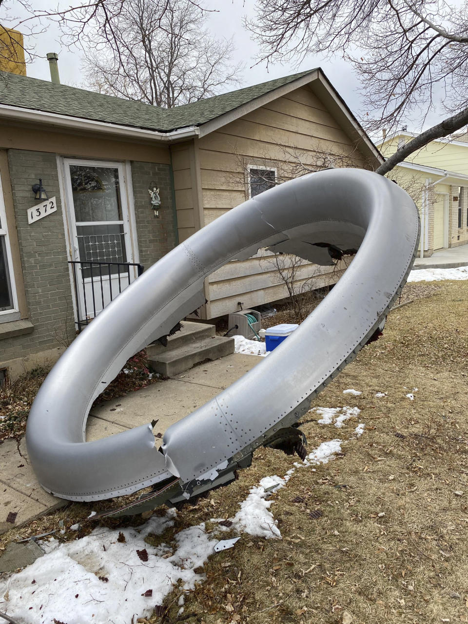 In this photo provided by the Broomfield Police Department on Twitter, debris is scattered in the front yard of a house at near 13th and Elmwood, Saturday, Feb. 20, 2021, in Broomfield, Colo. A commercial airliner dropped debris in Colorado neighborhoods during an emergency landing Saturday. The Broomfield Police Department said on Twitter that the plane landed safely at Denver International Airport and that no injuries had been reported from the incident. (Broomfield Police Department via AP)