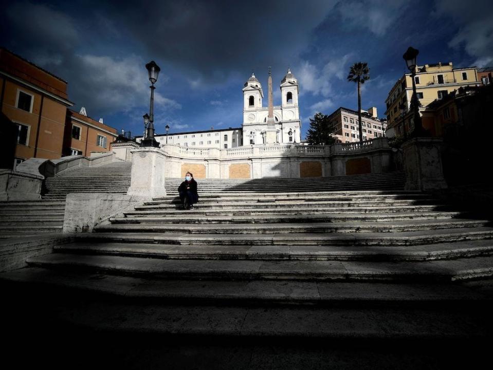 A face masked woman sits on empty Spanish Steps in downtown Rome on December 5, 2020.