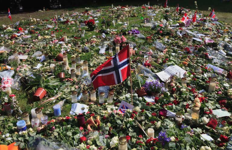 Se ve una bandera noruega entre flores y homenajes frente a la catedral de Oslo en Oslo, Noruega, en memoria de las víctimas del atentado con bomba del 22 de julio y el tiroteo violento, sábado 30 de julio de 2011