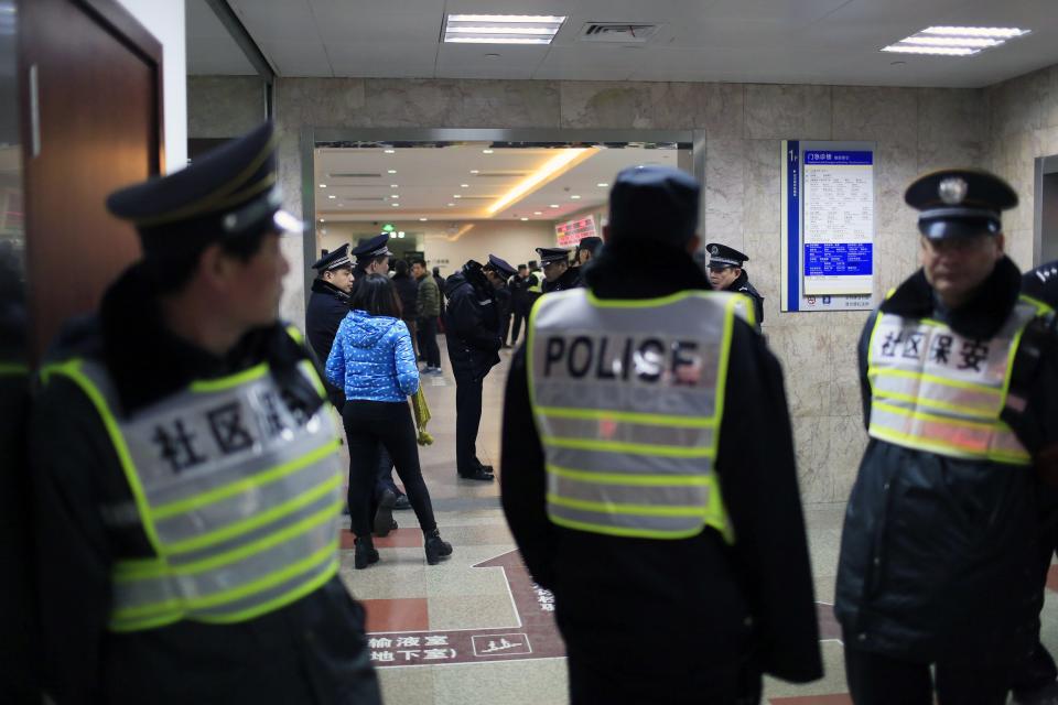 Security personnel and policemen stand next to an entrance to a hospital where injured people of a stampede incident are treated, in Shanghai