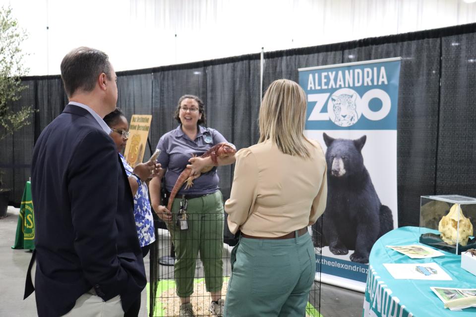 Alexandria Zoological Park's Curator of Education Catie Hirsh holds Big Red, an Argentinian red tegu, as she talks to attendees of Monday's Alexandria/Pineville Convention and Visitors' Bureau annual tourism luncheon.