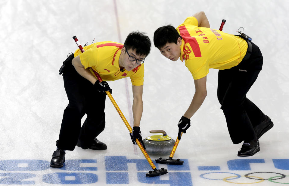 China's Zang Jialiang, left, and Ba Dexin, right, sweep the ice during the men's curling competition against Germany at the 2014 Winter Olympics, Wednesday, Feb. 12, 2014, in Sochi, Russia. (AP Photo/Wong Maye-E)