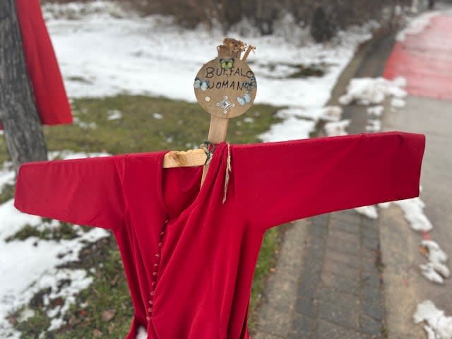 The name Buffalo Woman appears with a red dress along a pathway to Camp Marcedes near the Canadian Museum for Human Rights. (Alana Cole/CBC - image credit)