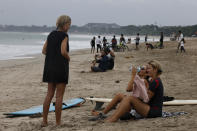 Tourists are seen at Kuta beach, Bali, Indonesia on Thursday, July 9, 2020. Indonesia's resort island of Bali reopened after a three-month virus lockdown Thursday, allowing local people and stranded foreign tourists to resume public activities before foreign arrivals resume in September. (AP Photo/Firdia Lisnawati)