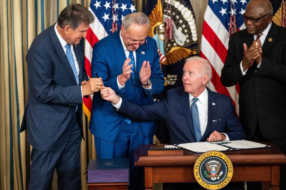 President Joe Biden, center, hands the pen used to sign H.R. 5376, the Inflation Reduction Act of 2022 into law, to Sen. Joe Manchin (D-WV) in the State Dining Room of the White House on Tuesday, Aug. 16, 2022 in Washington, DC.