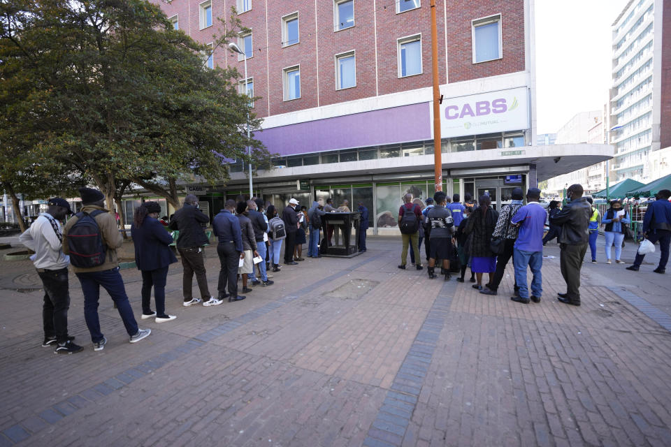 People queue to enter a bank, in Harare, Monday, July 25, 2022. Zimbabwe on Monday launched gold coins to be sold to the public to try to tame runaway inflation that has further eroded the country’s unstable currency. (AP Photo/Tsvangirayi Mukwazhi)