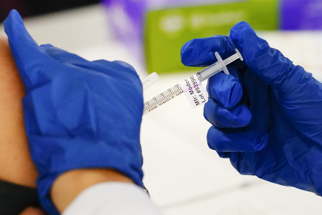 A health worker administers a dose of a Moderna COVID-19 vaccine.