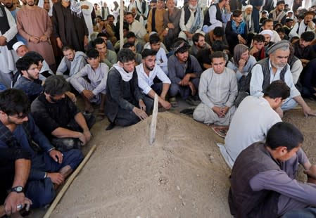 Afghan men attend the burial ceremony of the victims of a blast in a wedding in Kabul