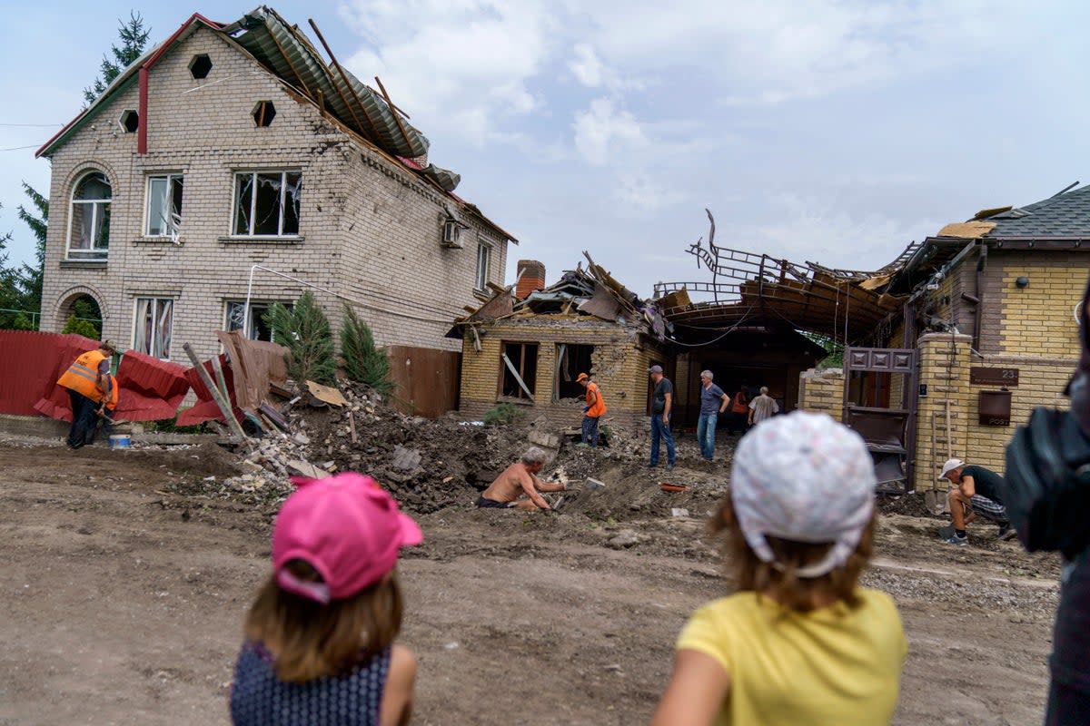 Children watch as workers clean up after a rocket strike on a house in Kramatorsk, in Donetsk region (AP)