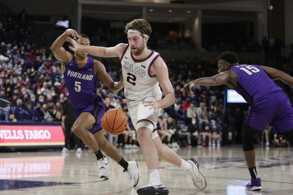 Gonzaga forward Drew Timme, center, drives the ball between Portland guard Chris Austin, left, and forward Chika Nduka during the second half of an NCAA college basketball game, Saturday, Jan. 29, 2022, in Spokane, Wash. Gonzaga won 104-72. (AP Photo/Young Kwak)