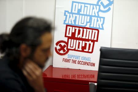 An employee of Peace Now, an Israeli NGO that tracks and opposes Jewish settlement in the occupied West Bank and East Jerusalem, works near a placard at their offices in Tel Aviv January 31, 2016. The placard in Hebrew reads, "Love Israel. Against the occupation". Picture taken January 31, 2016. REUTERS/Baz Ratner