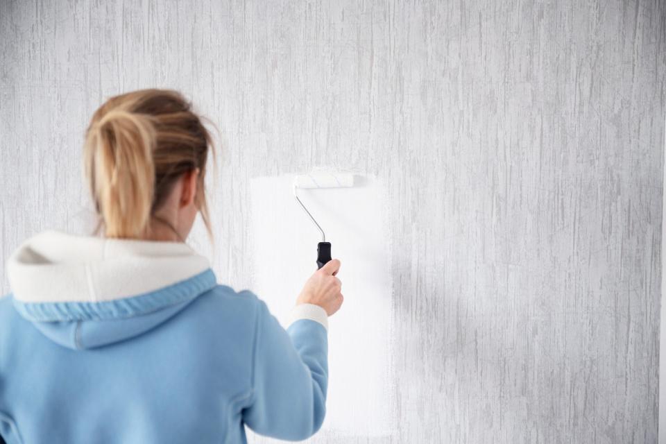 woman painting over wallpaper