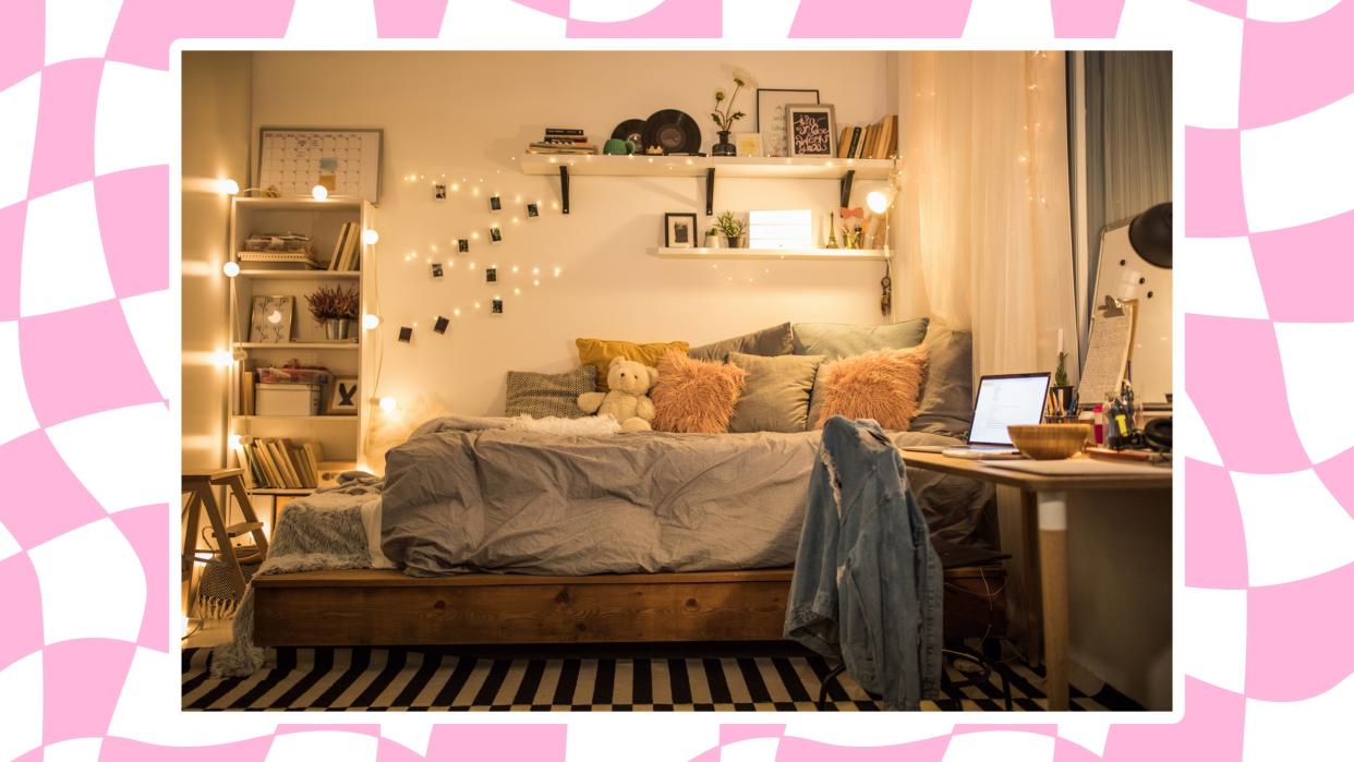  A dorm room with a bed, desk and fairy lights, shown on a checked pink and white background. 