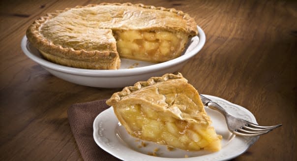 slice of apple pie with whole pie in background