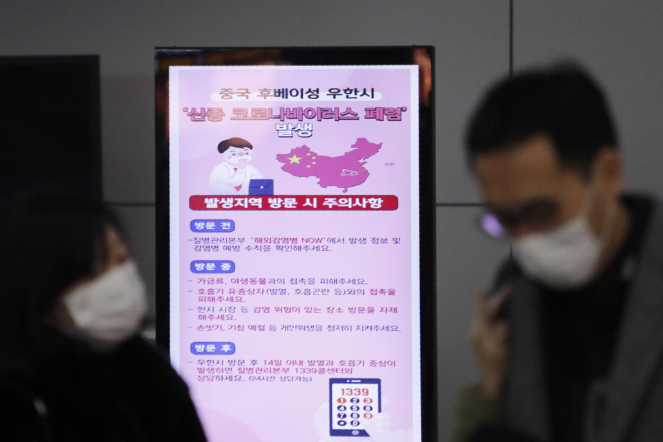 FILE - In this Jan. 27, 2020, file photo, a poster warning about coronavirus is seen as passengers wear masks in a departure lobby at Incheon International Airport in Incheon, South Korea. Health authorities are preparing for a possible pandemic as they work to contain a respiratory illness in China that's caused by a new virus. Governments are working to contain the virus by limiting travel, isolating sick people and keeping travelers returning from the affected region under quarantine to watch for symptoms. (AP Photo/Ahn Young-joon, File)