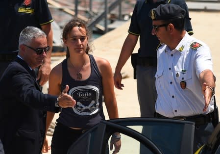 Carola Rackete, the 31-year-old Sea-Watch 3 captain, disembarks from a Finance police boat and is escorted to a car, in Porto Empedocle