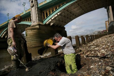 Mudlarks Andy Johansen and Ian Smith dig holes as they look for objects under Southwark Bridge on the bank of the River Thames in London, Britain May 22, 2016. REUTERS/Neil Hall