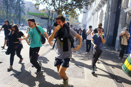 Demonstrators react to the effects of tear gas during a protest calling for changes in the education system in Santiago, Chile April 11, 2017. REUTERS/Ivan Alvarado