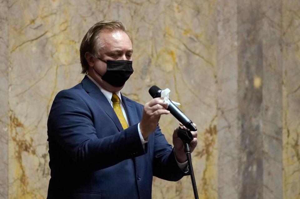 FILE - In this Jan. 11, 2021 file photo, Sen. Doug Ericksen, R-Ferndale, wipes off a microphone before speaking on the Senate floor on the first day of the 2021 legislative session at the Capitol in Olympia, Wash. The 2021 session of the Washington Legislature ended Sunday, April 25 and lawmakers had no shortage of weighty topics to consider while having to conduct their work amid a pandemic that meant most meetings and votes were conducted remotely. The Capitol building was also closed to the public since last year due to the COVID-19 pandemic, and was surrounded by security fencing and national guard members at times due to fears of protests. (AP Photo/Ted S. Warren, File)