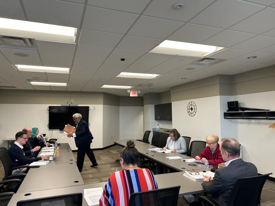 Attorney Todd Perkins, standing, passes out documents during a Macomb County Ethics Board meeting April 16, 2024, in Mount Clemens. He is representing Macomb County Prosecutor Peter Lucido, who has two ethics complaints against him.