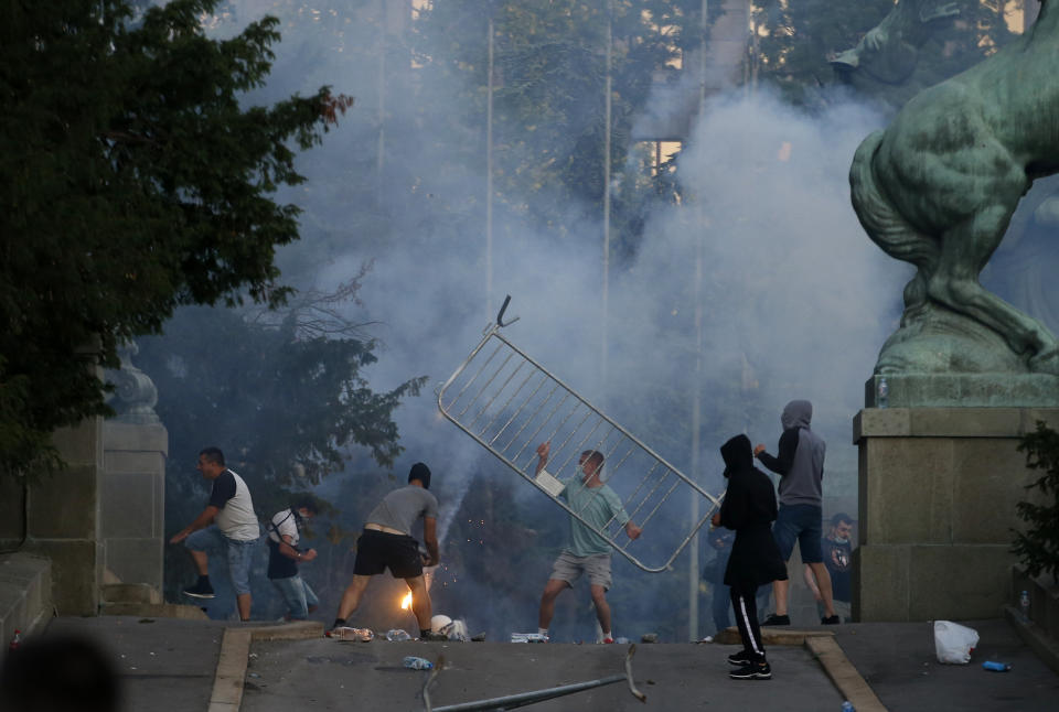 Protesters clash with Serbian riot police in Belgrade, Serbia, Wednesday, July 8, 2020. Police have fired tear gas at protesters in Serbia's capital during the second day of demonstrations against the president's handling of the country's coronavirus outbreak. President Aleksandar Vucic backtracked on his plans to reinstate a coronavirus lockdown in Belgrade this week, but it didn't stop people from firing flares and throwing stones while trying to storm the downtown parliament building. (AP Photo/Darko Vojinovic)