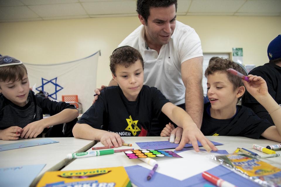 From left Coby Shaw, 10, makes "Thank You" cards with Azi Knoll, 11, his brother Caleb Knoll, and his father David Knoll, during a community service day to mark the one year anniversary of the Tree of Life synagogue shooting, Sunday, Oct. 27, 2019, in Pittsburgh. The cards will be sent to business and organizations who reached out to Pittsburgh's Jewish community with notes and also in-kind donations after the attack last year. (AP Photo/Rebecca Droke)