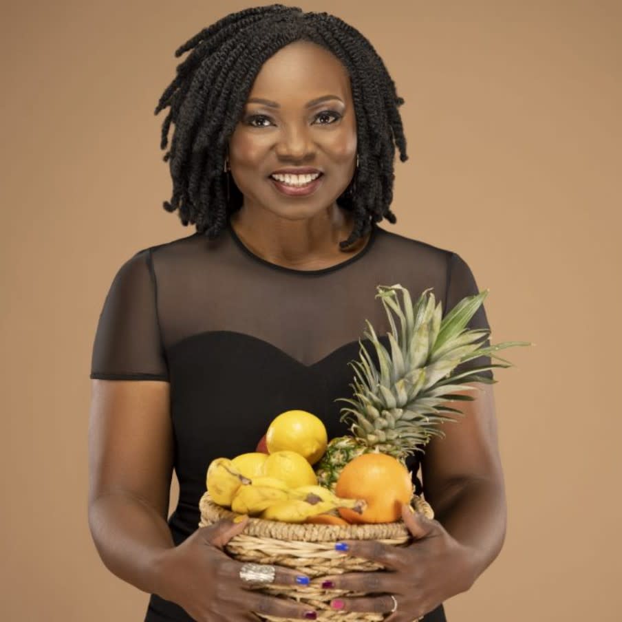  Yummy Spoonfuls founder Agatha Achindu smiling while holding a bowl of food she prepared. 