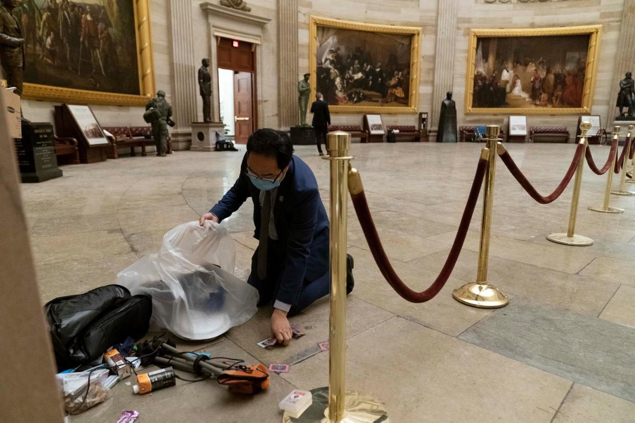 Rep. Andy Kim, D-N.J., cleans up debris and personal belongings strewn across the floor of the Rotunda in the early morning hours of Thursday, Jan. 7, 2021, after protesters stormed the Capitol in Washington on Wednesday.