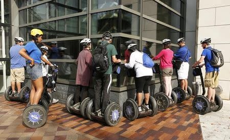 Tourists on Segways peer into the window of the Newseum, one of the few attractions open to tourists in Washington, October 3, 2013. REUTERS/Kevin Lamarque