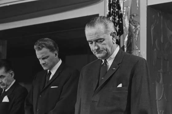 President Lyndon Johnson prays with Dr. Billy Graham at the annual Presidential Prayer Breakfast held in Washington, 1964.<span class="copyright">Bettmann Archive/Getty Images</span>