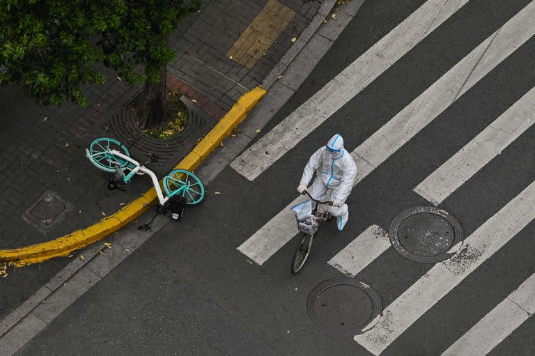 Un trabajador con equipo protector anda en bicicleta por las calles de Shangh&#xe1;i