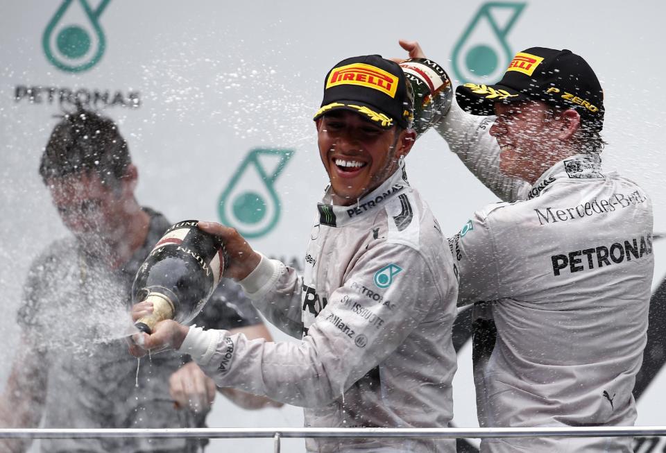 Mercedes driver Lewis Hamilton of Britain sprays champagne on the podium with teammate Nico Rosberg, right, after winning the the Malaysian Formula One Grand Prix at Sepang International Circuit in Sepang, Malaysia, Sunday, March 30, 2014. Rosberg finished in second place. (AP Photo/Vincent Thian)