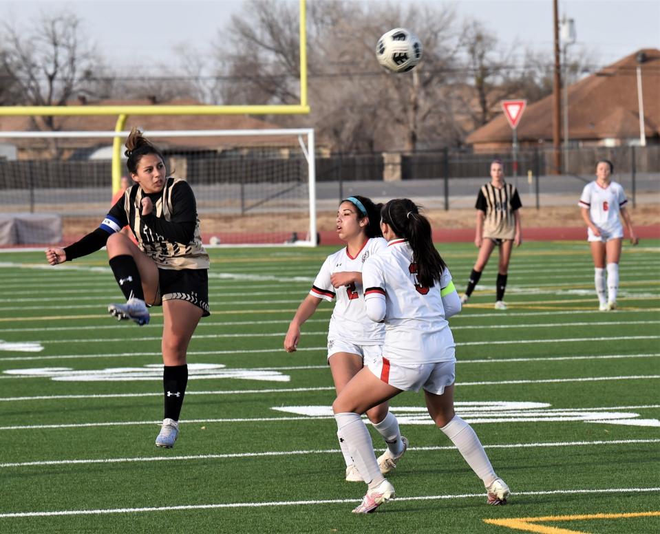 Abilene High's Justine Martinez, left, kicks the ball over a pair of Lubbock-Cooper defenders in the first half.