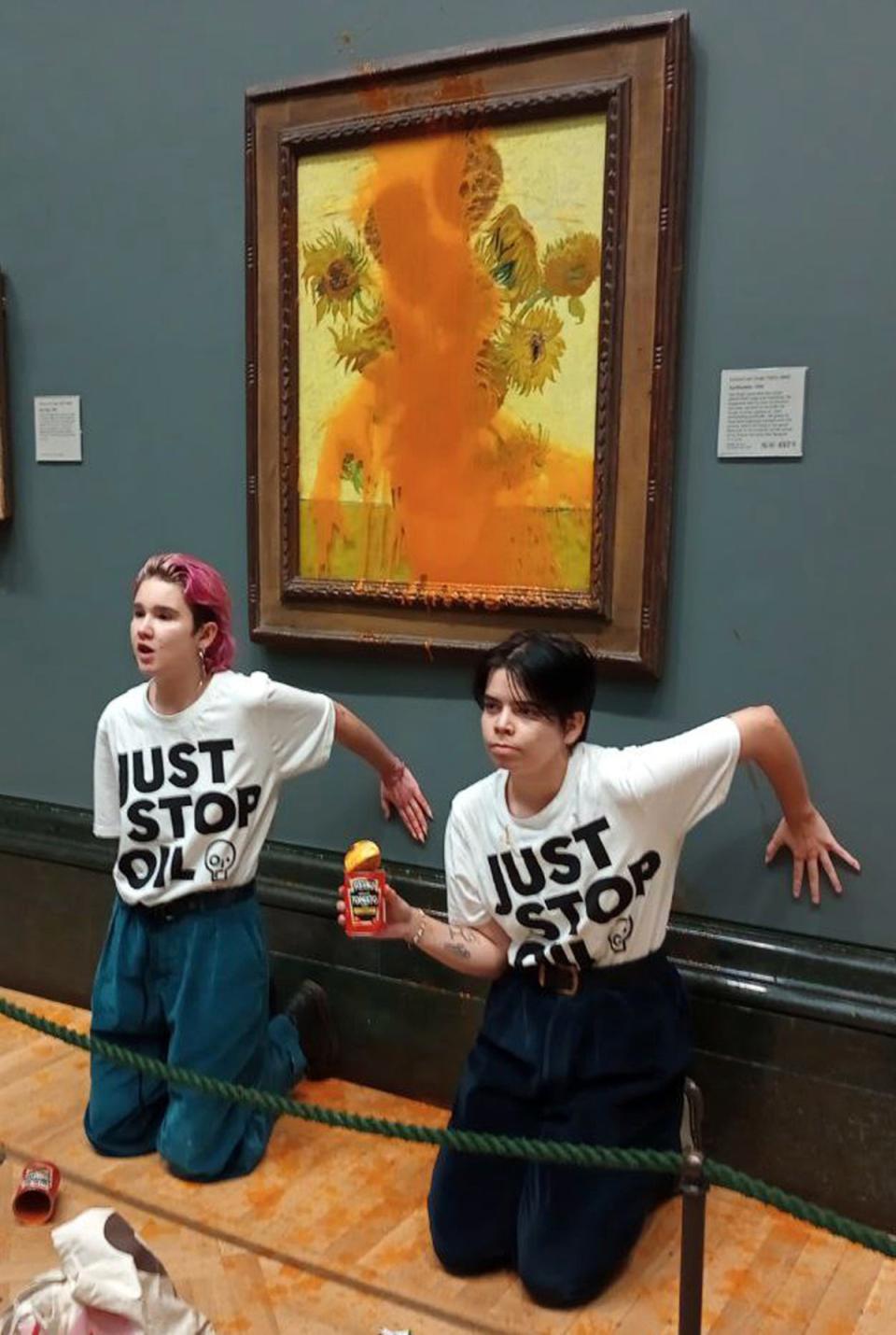 Two protesters who have thrown tinned soup at Vincent Van Gogh’s famous 1888 work Sunflowers at the National Gallery in London, Friday Oct. 14, 2022. (AP)
