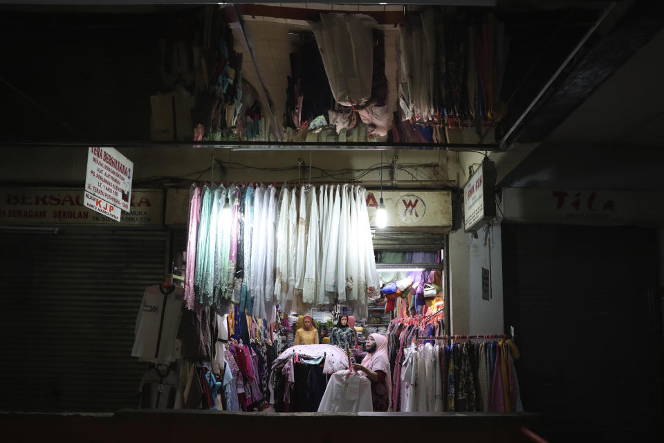 Cloth venders prepare to open their shops amid fears of the new coronavirus outbreak at a market in Jakarta, Indonesia Friday, May 22, 2020. (AP Photo/Achmad Ibrahim)