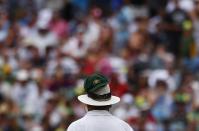 Australia's Nathan Lyon's cap is seen on umpire Marais Erasmus's hat as he bowls during the fourth day of the second Ashes test cricket match against England at the Adelaide Oval December 8, 2013.