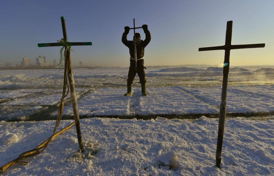 A worker stabs an iron pike into the frozen Songhua River as he takes giant ice cubes to make sculptures for the upcoming 30th Harbin Ice and Snow Festival, in Harbin