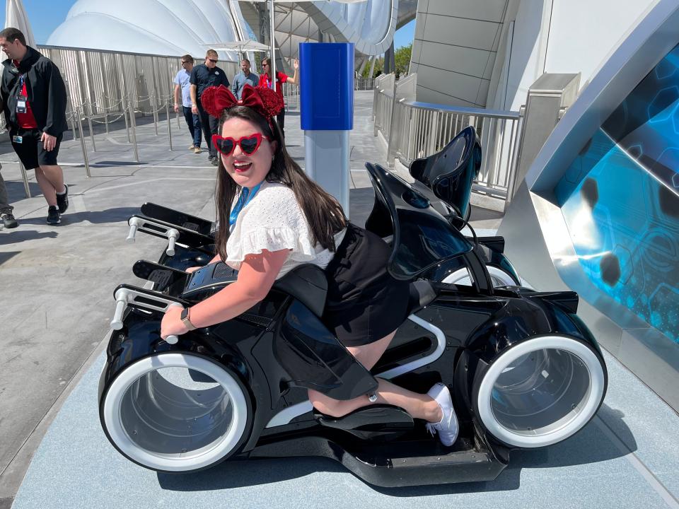 megan posing for a photo in the tron roller coaster test seat outside the attraction at magic kingdom