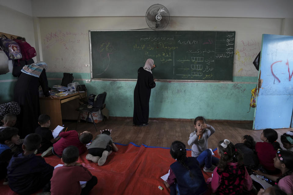 Manal Al Buhaisi works with children at a makeshift class in Deir al Balah, on Sunday, April 21, 2024. Since the war erupted Oct 7, all schools in Gaza have closed, and nearly 90% of school buildings are damaged or destroyed, according to aid groups. (AP Photo/Abdel Kareen Hana)