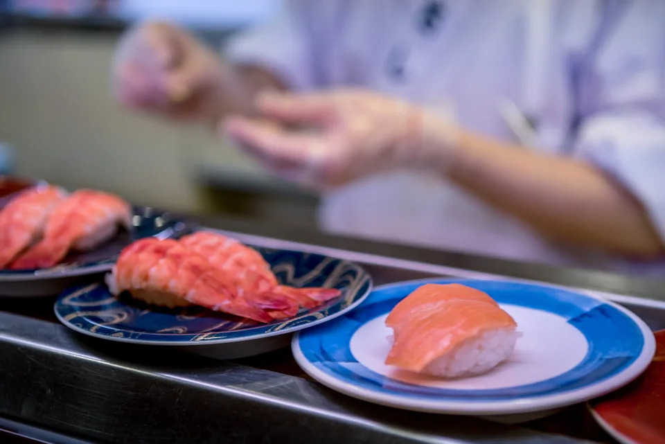 Sushi on conveyor belt in a Japan restaurant. Traditional Kaitenzushi Japanese food. Shushi Go Round is a famous form of fast food in Asia, also known as sushi train.