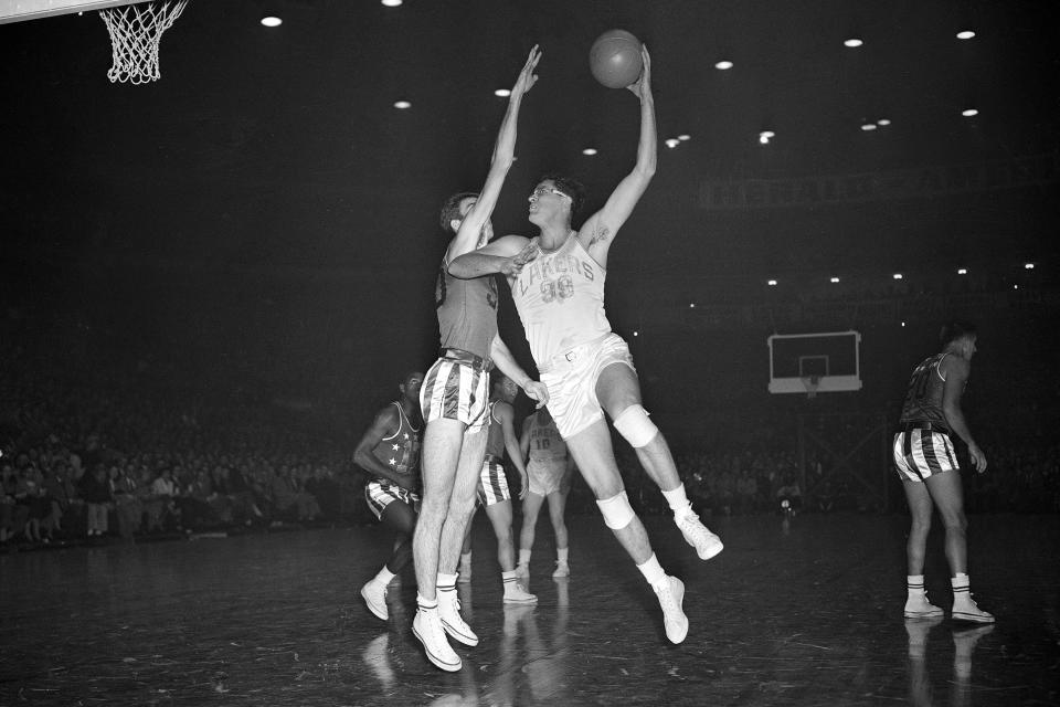 FILE - In this Oct. 26, 1949, file photo, George Mikan (99) Minneapolis Lakers Center, shoots in front of Ed MaCauley at the Chicago Stadium in Chicago. (AP Photo/Ed Maloney, File)
