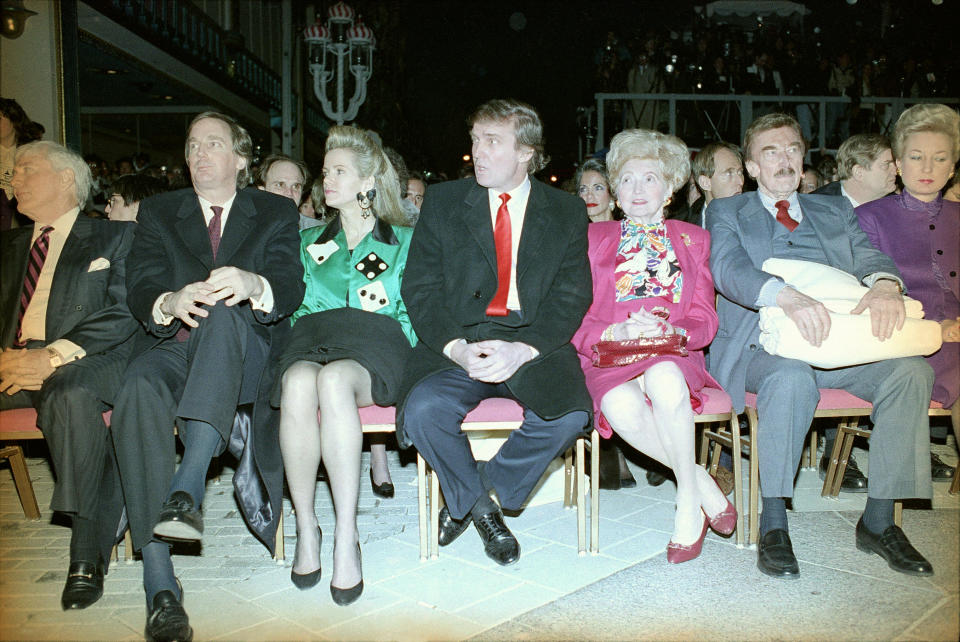 Donald Trump, center, sits with hands folded at the Trump Taj Mahal in Atlantic City, N.J., April 6, 1990, before the start of grand opening ceremonies. Trump attended the gala with his parents, Mary and Fred, and sister US District Court Judge Maryanne Trump Barry, right, and brother Robert Trump, left, and his wife Blaine Trump, third from left wearing green. Trump was dateless. (AP Photo/Charles Rex Arbogast)