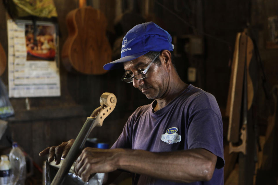 In this Dec. 11, 2012 photo, Nicolas Gomez makes a violin out of recycled materials at his home in Cateura, a vast landfill outside Paraguay's capital of Asuncion, Paraguay. Gomez, a trash picker and former carpenter, was asked by Favio Chavez, the creator of "The Orchestra of Instruments Recycled From Cateura," to make instruments out of materials from the dump to help keep the younger kids occupied. "I only studied until the fifth grade because I had to go work breaking rocks in the quarries," said Gomez, 48. (AP Photo/Jorge Saenz)