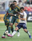 LA Galaxy's Joseph Paintsil, left, and Vancouver Whitecaps' Andres Cubas vie for the ball as Galaxy's Mark Delgado, back, watches during the first half of an MLS soccer match Saturday, April 13, 2024, in Vancouver, British Columbia. (Darryl Dyck/The Canadian Press via AP)