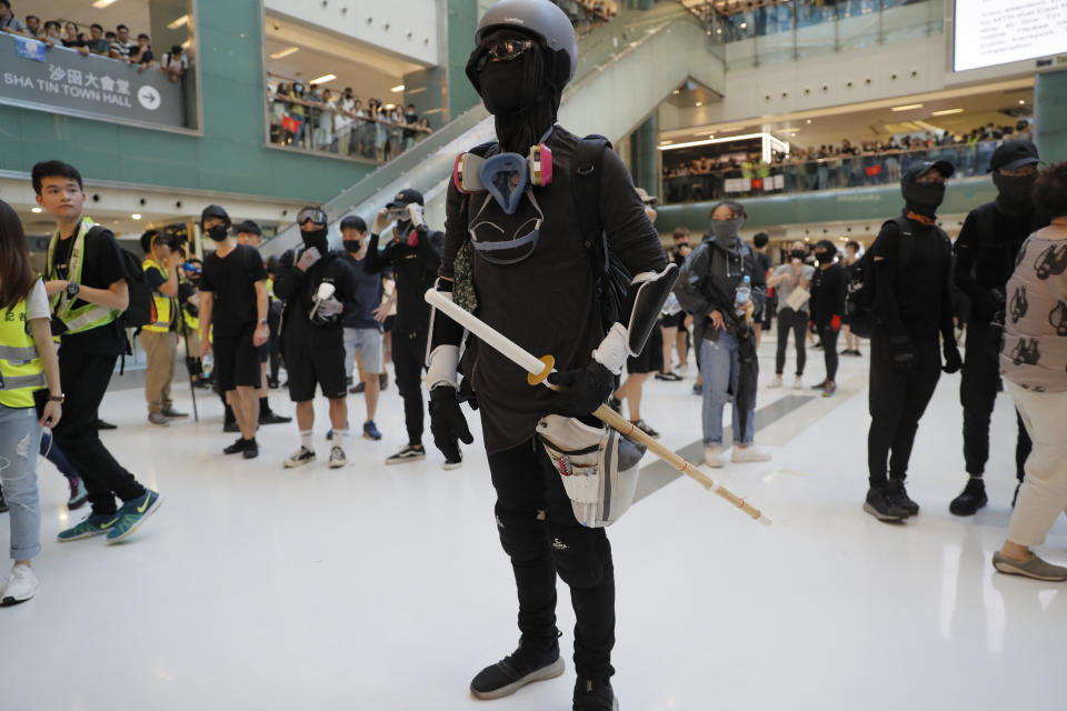 A protester armed with a wooden weapon stands in a mall during a protest in Hong Kong on Sunday, Sept. 22, 2019. Protesters smashed surveillance cameras and electronic ticket sensors in a subway station, as pro-democracy demonstrations took a violent turn once again. (AP Photo/Kin Cheung)